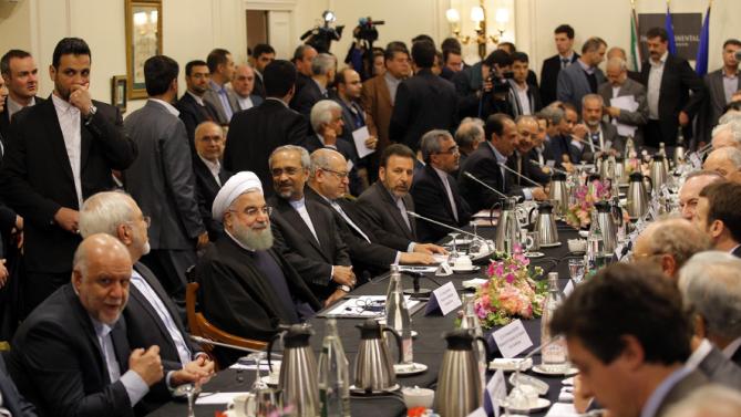 Iranian President Hassan Rouhani, third left seated, attends a meeting with French Economy Minister Emmanuel Macron and French business leaders in Paris. (AP Photo/Christophe Ena)